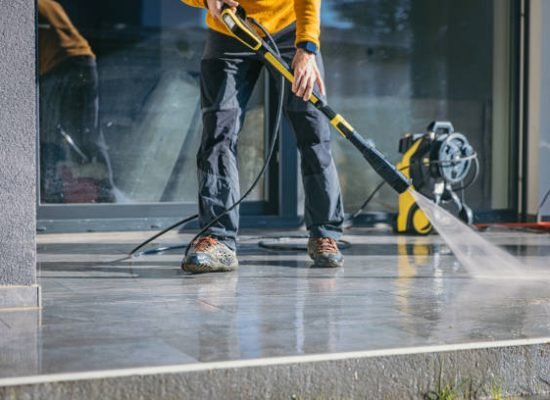 Man cleaning the terrace with high pressure cleaner on beautiful sunny day.